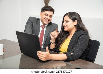 Two Happy Young Indian Business Colleagues Working Together In Office, Corporate Male And Female Wearing Formal Suit Using Laptop.