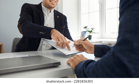 Two happy young people make a business deal and sign a contract agreement in the office. Friendly, smiling agent shows his client where to put a signature. Cropped shot. Banner background