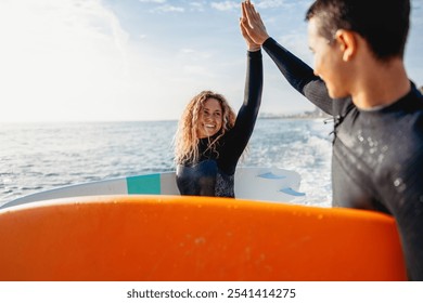 Two happy young surfers with surfboard prepares to hit the waves at sunset. Sports active vacation - Powered by Shutterstock