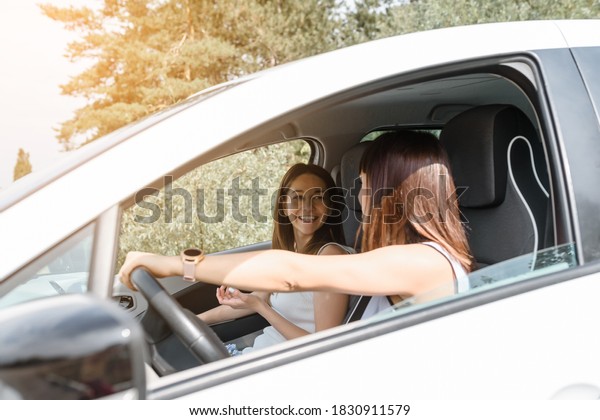 Two happy young women\
friends are driving a car and enjoy the company. Travel with you\
friend concept