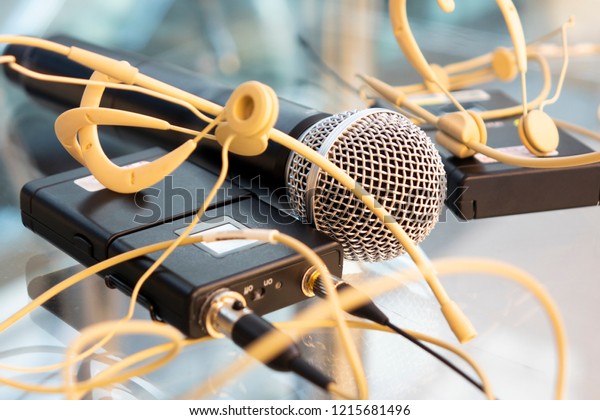 Two head set wireless microphones transmitter and\
hand microphone; wireless microphone reciever on glass table in tv\
studio