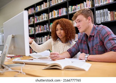 Two Heads Are Better Than One. Shot Of Two Students Working Together At A Computer In A University Library.