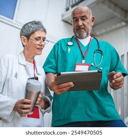 Two healthcare professionals in conversation, use digital tablet on staircase outdoor - Powered by Shutterstock