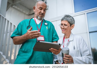 Two healthcare professionals in conversation, use digital tablet on staircase outdoor - Powered by Shutterstock