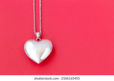 Two heart pendants on a chain on a red background right and left, Valentine's day, flat lay, copy space