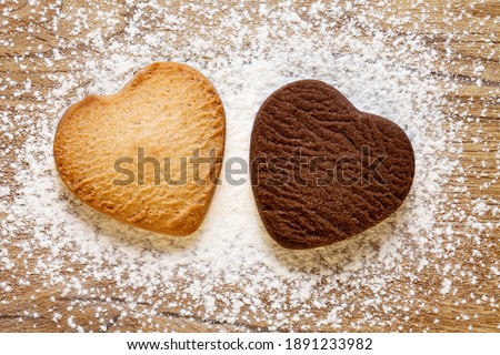 Two heart shaped cookies on wooden background. Baked butter and chocolate cookies. Valentines day concept. Top view.