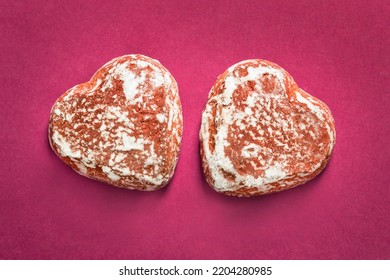 Two heart shaped gingerbreads on pink background