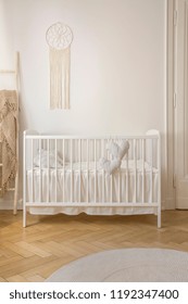 Two heart shaped pillows placed on baby crib standing in white room interior with macrame on wall and herringbone parquet in the real photo - Shutterstock ID 1192347400