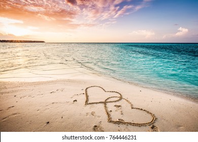Two hearts drawn on a sandy beach by the sea. Sunset view. Love symbol. - Powered by Shutterstock