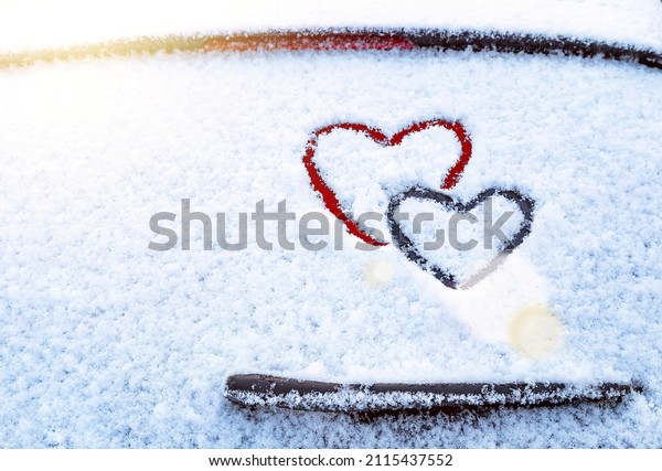 Two hearts (symbol of love) hand drawing on\
snow on the glass above windshield wiper of car. Valentines day,\
love, honeymoon, winter, transport concept. Copy space. Empty place\
for your messeges.
