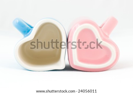 Two heart-shape blue and pink cups on white background with narrow depth of field