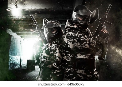 Two heavily armed masked paintball soldier on post apocalyptic background. Ad concept.