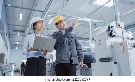 Two Heavy Industry Employees in Hard Hats Discussing Job Assignments at the Factory, Using Laptop Computer. Asian Engineer and Technician at Work Checking Safety Procedures. - Powered by Shutterstock