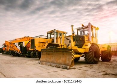Zwei schwere Traktoren, ein Bagger und andere Baumaschinen in der Morgensonne