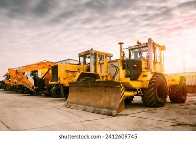 Two heavy wheeled tractor one excavator and other construction machinery in the morning sun