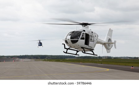 Two Helicopters Landing On A Runway.