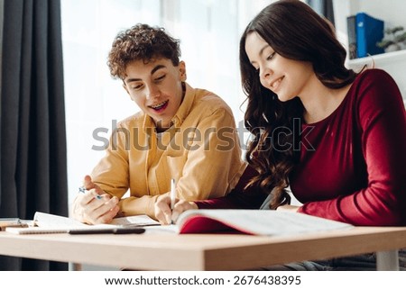 Two high school students collaborating on a project, exchanging ideas and working together in a classroom filled with books and notes