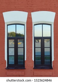 Two high windows in an old red brick building, European style