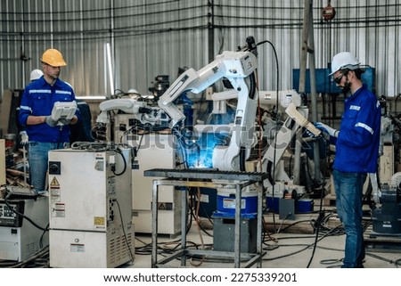 Two highly competent robotic operators collaborate to configure new automation using a computer-controlled panel display. The robot's coordination system for welding, cutting, and milling in a factory