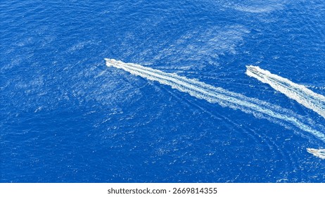 Two high-speed boats create dynamic trails in the vibrant blue water as they race across the sparkling surface under a bright, cloudless sky, showcasing the thrill of marine exploration.