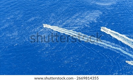 Two high-speed boats create dynamic trails in the vibrant blue water as they race across the sparkling surface under a bright, cloudless sky, showcasing the thrill of marine exploration.