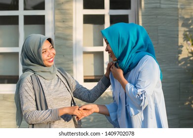 Two Hijab Women Neighbors Meet And Say Hi While Smiling And Shake Hands In Front Of Their House On A Sunny Day