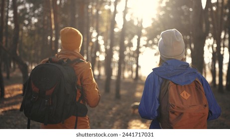 two hiker work as team. with backpacks walking in winter in a forest park in the sunny glare at sunset. sun Two tourists travel hiking in forest park, overcoming difficulties, teamwork concept - Powered by Shutterstock