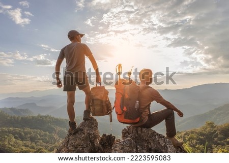 Two hikers with backpack relaxing on top mountain landscape enjoy beautiful landscape view sunset.Hiker men's hiking living healthy active lifestyle.