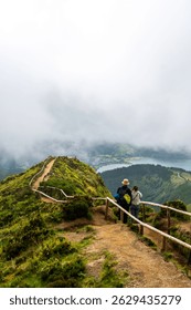 Dos excursionistas hacen una pausa en el riel de madera del mirador de Boca do Inferno sobre los lagos Sete Cidades