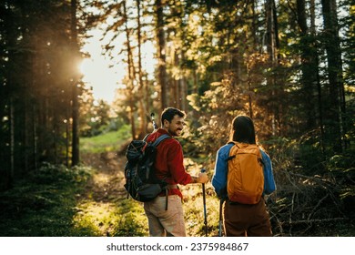 Two hikers, representing diversity, traverse a rugged terrain, their trusty backpacks packed with essentials as they navigate the natural wonders with their sturdy walking sticks - Powered by Shutterstock