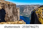 Two hikers stand on the edge of Kjeragbolten, Norway, a famous cliff in Norway, couple of men and women visit Kjeragbolten, Norway