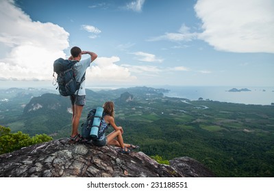 Two hikers standing on top of the mountain with valley on the background