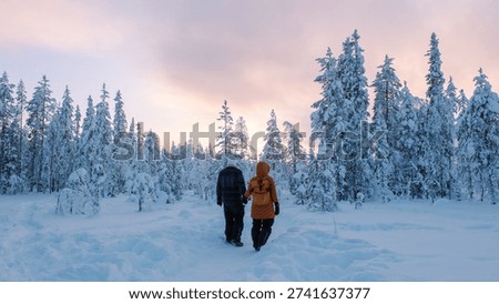 Two hikers stroll through a tranquil, snow-draped forest in Akaslompolo, Lapland.Akaslompolo, Lapland Finland