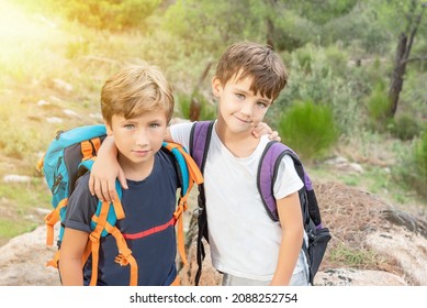 Two Hiking Kids With Their Backpacks In The Bush Happy To Reach The End Of The Trail. Boy Scouts Hiking In The Forest