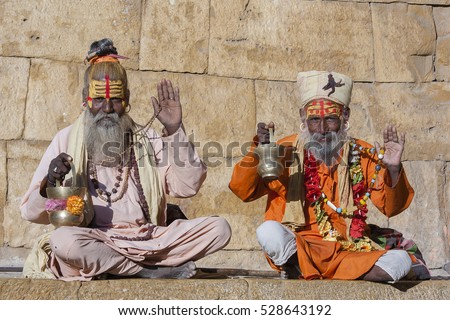 Two hindu sadhu holy man, sits on the ghat, seeks alms on the street in Jaisalmer, Rajasthan, India. Close up