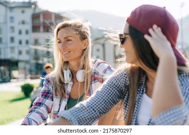 Two hipster women sitting relaxed chatting outside in the summer at the skatepark. - Powered by Shutterstock