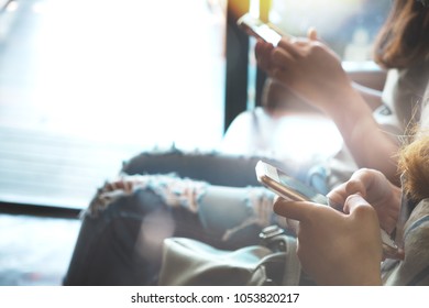 Two of  hipsters woman sitting on sofa holding en hands and using mobile phone. Coworking young women teamwork. business marketing online concept. retro film effect, blurred background - Shutterstock ID 1053820217