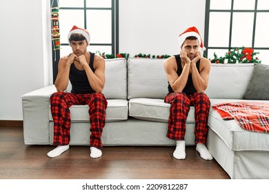 Two Hispanic Men Couple Arguing Sitting By Christmas Tree At Home