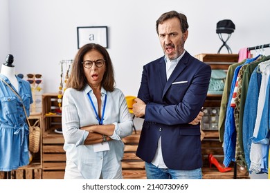 Two Hispanic People Working As Manager At Retail Boutique In Shock Face, Looking Skeptical And Sarcastic, Surprised With Open Mouth 