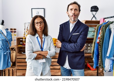 Two Hispanic People Working As Manager At Retail Boutique Making Fish Face With Mouth And Squinting Eyes,comical. 