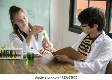 Two Hispanic Scientist Mixing Chemicals In Lap