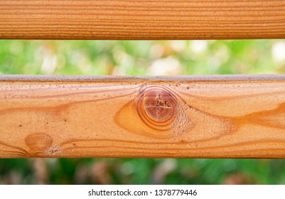 Two horizontal parallel wooden boards with interesting structure against blurred green grass. Back of garden bench. Closeup. Selective focus