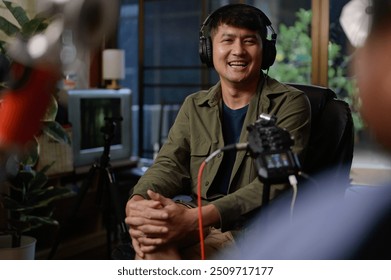 Two hosts of podcasts a happy radio host in a chic studio, one speaking into the microphone as the other listens intently while donning headphones to record a podcast. - Powered by Shutterstock