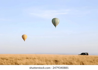 Two hot air balloons floating over a golden field with a vehicle in the distance. - Powered by Shutterstock