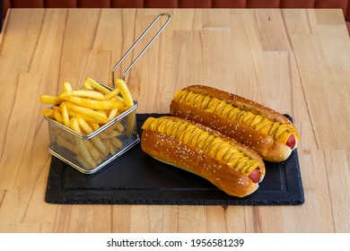 Two Hot Dogs With Cheese And Mustard Next To Potato Chips On A Wooden Table, After Serving Buying