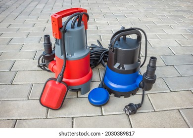 Two household submersible pump with plastic housings  on stone floor of courtyard
