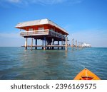 Two houses of historic Stiltsville in Biscayne Bay with many marine birds seen from an orange kayak.                            