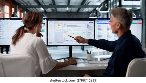 Two HR Managers Using Software On Computers To Track Employee Performance.