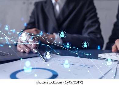 Two HR specialists man and woman analyzing the market of alumni to boost the intern program at international consulting company. Hiring new talented officers. Social media hologram icons. - Shutterstock ID 1945720192