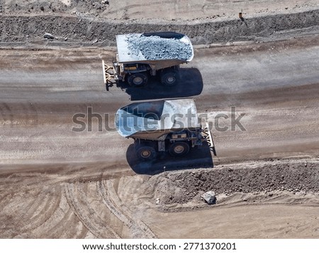 Two huge CAEX dump trucks crossing paths during the mineral transport process